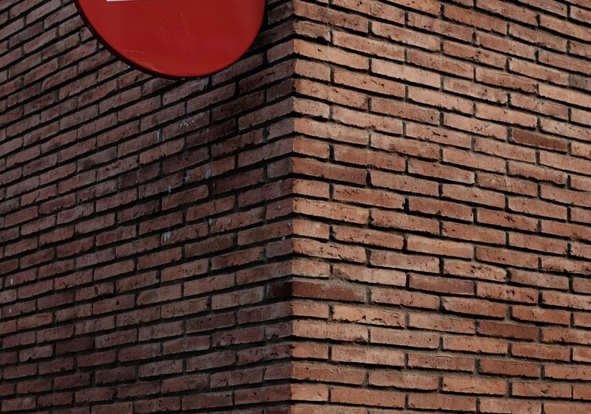 red and white signage on red brick wall at daytime