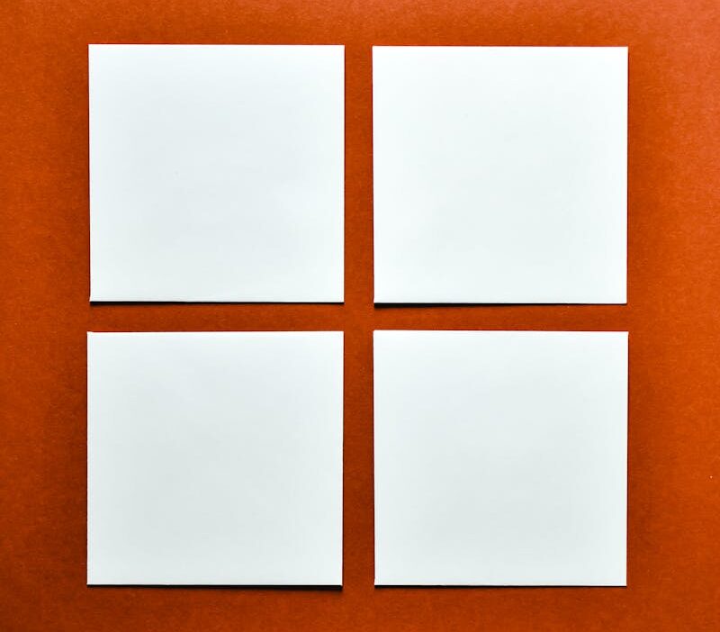 Four white paper squares arranged on a vibrant orange background, perfect for mockups.