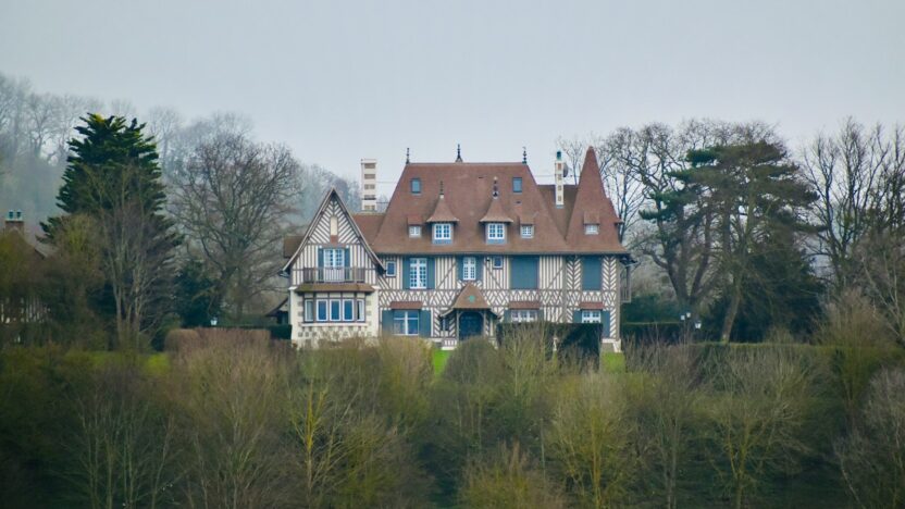 white and brown concrete house surrounded by green trees under white sky during daytime